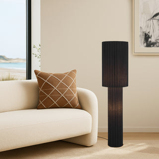 Alcona black floor lamp in contemporary living room beside neutral sofa, providing ambient illumination.