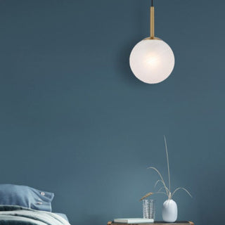 Spherical pendant light hanging against a dark blue wall with minimal decor.