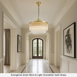Elegant hallway with a gold chandelier, framed artwork, and large French doors.