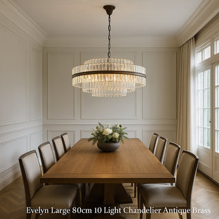 Dining room with a large chandelier hanging above a wooden table with a floral centerpiece.