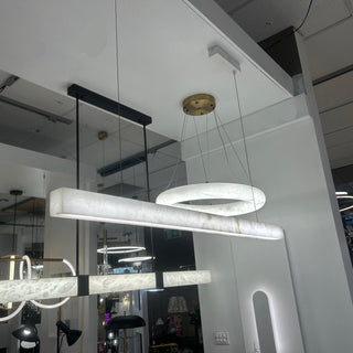 Modern chandeliers hanging from a ceiling in a showroom setting.