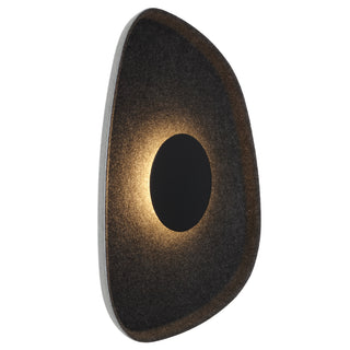 A wall light fixture with a textured surface and a circular LED light source visible through an opening in the center.
