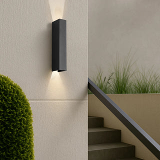 Ryland Black exterior wall light installed outdoors beside steps, emitting warm up and down light, architectural outdoor lighting.