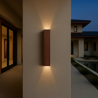 Ryland Rust wall light mounted on exterior wall near entryway at dusk, producing warm up and down illumination.