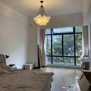 Modern bedroom with a chandelier, bed, and large window.