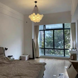 Modern bedroom with a chandelier, bed, and large window.