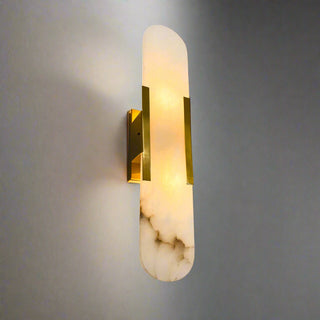 Wall sconce with marble base and gold accents on a gray wall