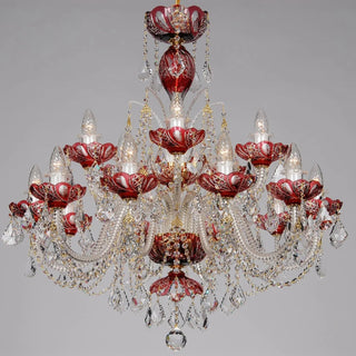 An ornate multi-tier chandelier featuring red glass cups and clear crystal prisms, shown against a neutral gray background.