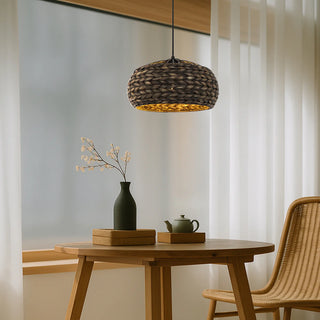 Woven pendant light over a wooden table with decorative items and a chair.