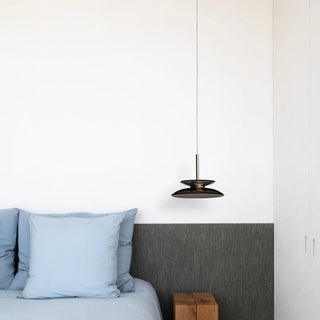 Modern bedroom with a bed, wooden side table, and pendant light.
