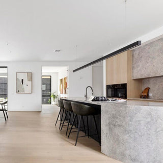 Modern living room and kitchen with a brown leather sofa and kitchen island.