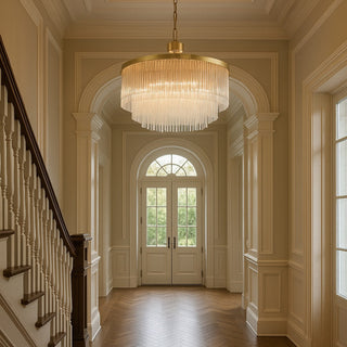 Luxurious hallway with a chandelier, wooden staircase, and arched door.