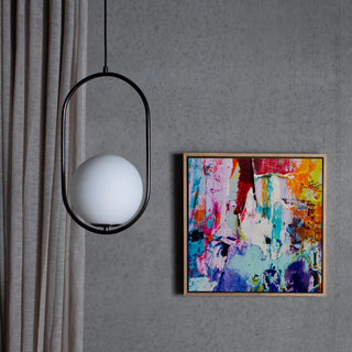 Colorful abstract painting on a gray wall with a modern pendant light and plant.
