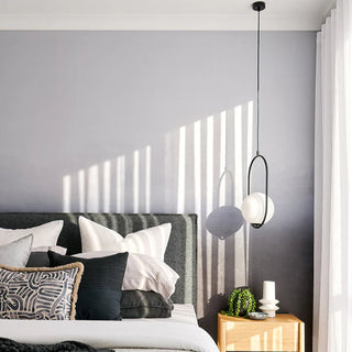 Modern bedroom with a bed, decorative pillows, and a pendant light.