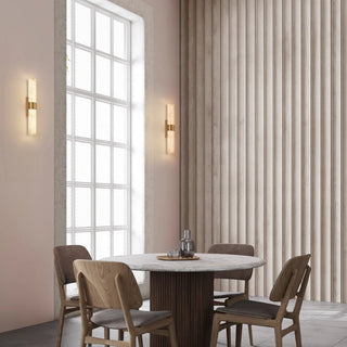 Two illuminated Flecha wall lights installed vertically beside a tall window in a neutral dining room