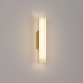 Flecha Angled small wall light illuminated, showing its faux marble diffuser with decorative veining and brass highlights.