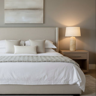 Table lamp with a beige ceramic base and a white lampshade on a white background