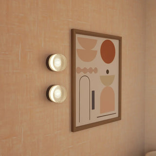 Two wall-mounted lights and a framed abstract art piece on a peach-colored wall.
