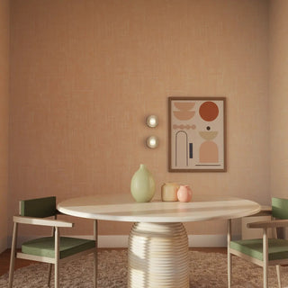 Dining area with a round table and chairs against a beige wall with abstract art.