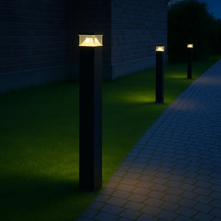 Decorative outdoor lights on black posts illuminating a pathway next to a brick wall.