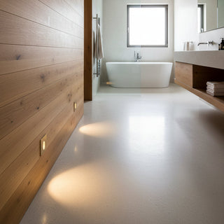 A modern minimalist bathroom interior with a white freestanding bathtub centered in the background, a long wall of light wood paneling on the left, a floating vanity with a mirror on the right, and a bright window at the back.
