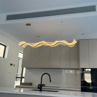 Modern kitchen with white cabinets, black faucet, and decorative light fixture.