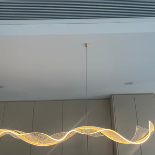 Modern ceiling light fixture with wavy design in a room with gray walls.