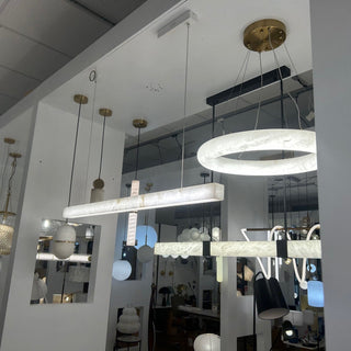 Various marble pendant lights displayed in a Davoluce Lighting showroom setting.