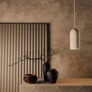Decorative vases and a pendant light in a room with a textured wall.