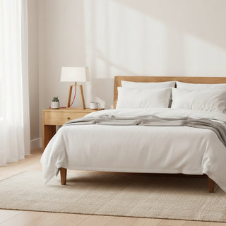 Neatly made bed with white bedding and wooden headboard in a bright bedroom.