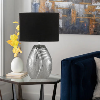 Klee ceramic table lamp with chrome detailing on bedside table