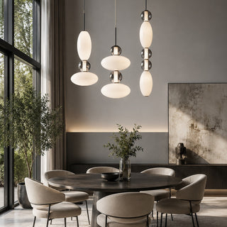Modern dining room with round table and chairs, featuring pendant lights and large windows.