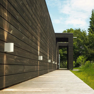 Modern building with wooden facade and outdoor lighting under a blue sky.
