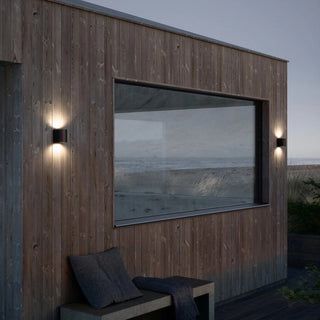 Wooden building with a large window overlooking the ocean at dusk.