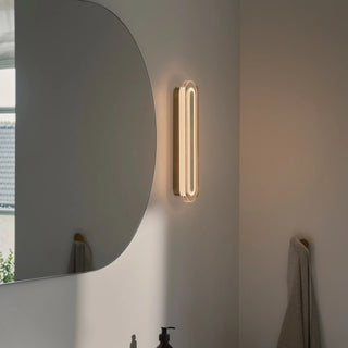 Nordlux Cavara brass LED wall light installed vertically beside bathroom mirror
