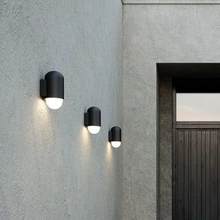 Modern exterior of a house with a dark door and wall-mounted lights.