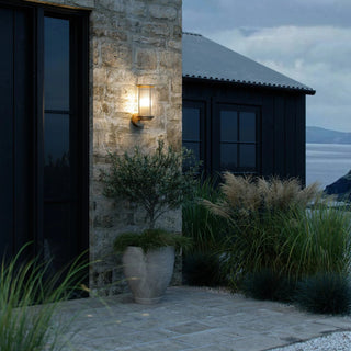 Stone building exterior with a wall-mounted light fixture and potted plant.