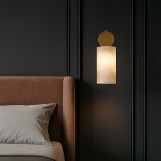 Modern pendant light hanging above a bed with a dark wall background