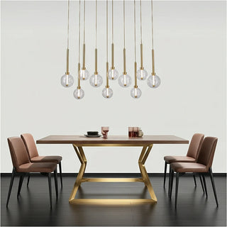 Dining table with gold base and chairs, featuring modern pendant lights.