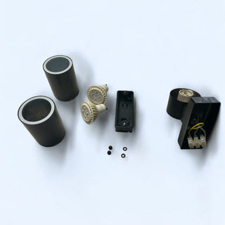 Set of electronic components including black cylindrical parts and a small black box with wires on a white background.
