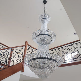 Crystal chandelier hanging in a room with a staircase in the background