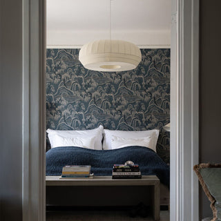 Bedroom with patterned wallpaper, blue bedding, and a lamp.