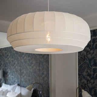 Off White pendant light hanging in a room with patterned wallpaper and a sofa.