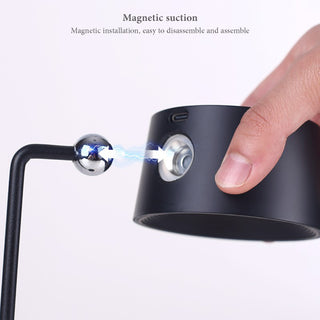 Magnetic suction demonstration with a hand holding a black cylindrical object and a metallic sphere.