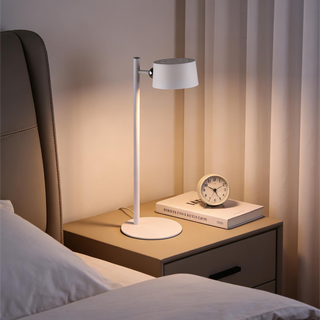 Table lamp on a nightstand next to a bed with soft lighting
