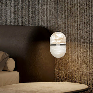 Modern pendant light hanging in a bedroom with a textured wall next to bed