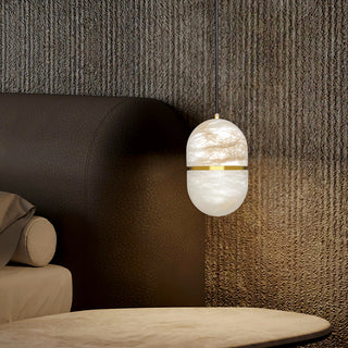 Modern pendant light hanging in a bedroom with textured walls next to bed