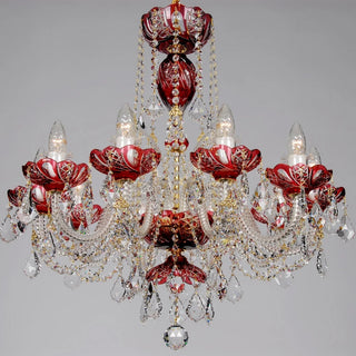 A red and gold Venetian-style crystal chandelier with multiple arms, red glass floral accents, and hanging clear crystal prisms, shown against a neutral gray background.