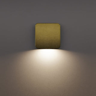 Lumena AQL-512 square wall light emitting a warm glow on a dark wall.