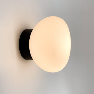Wall-mounted light fixture with a round beige lampshade on a gray background